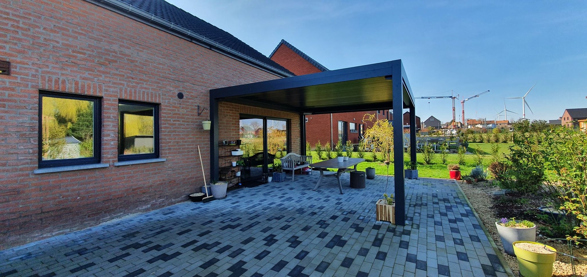 Pergola à lames orientables adossée à une façade en brique