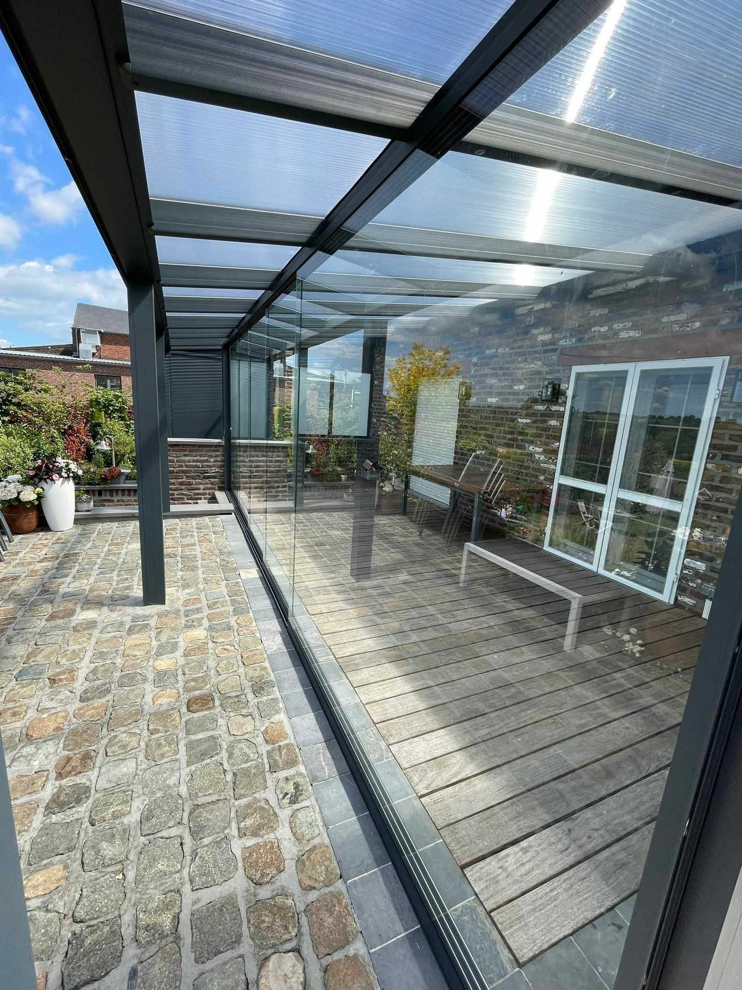 Pergola à toiture vitrée sur une terrasse en pavés de pierre