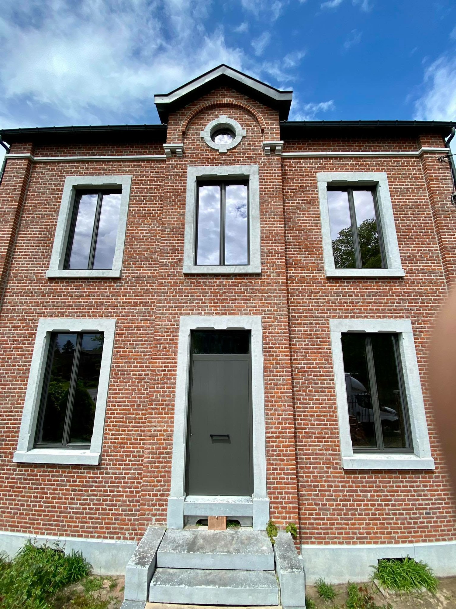 Maison de maître en brique avec châssis blancs et porte d'entrée anthracite