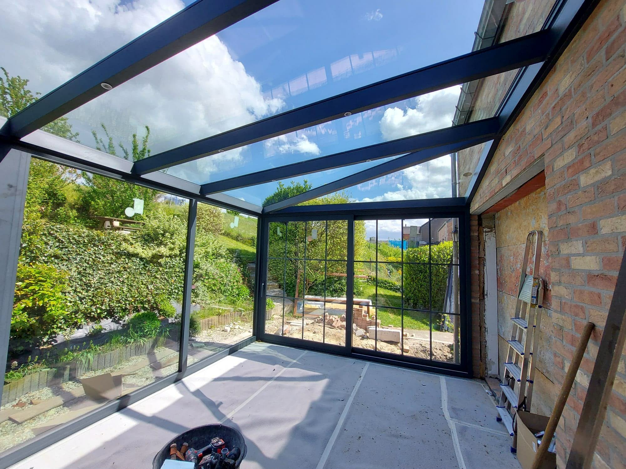 Pergola vitrée adossée à un mur en brique, terrasse abritée
