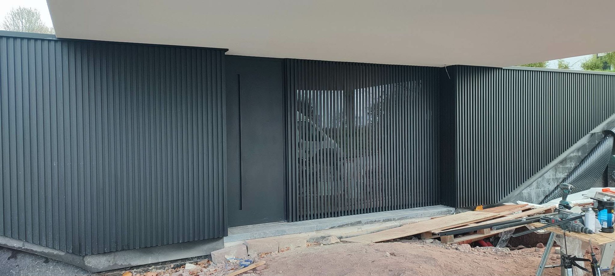 Bardage aluminium à lames verticales sombres posé en cours de chantier