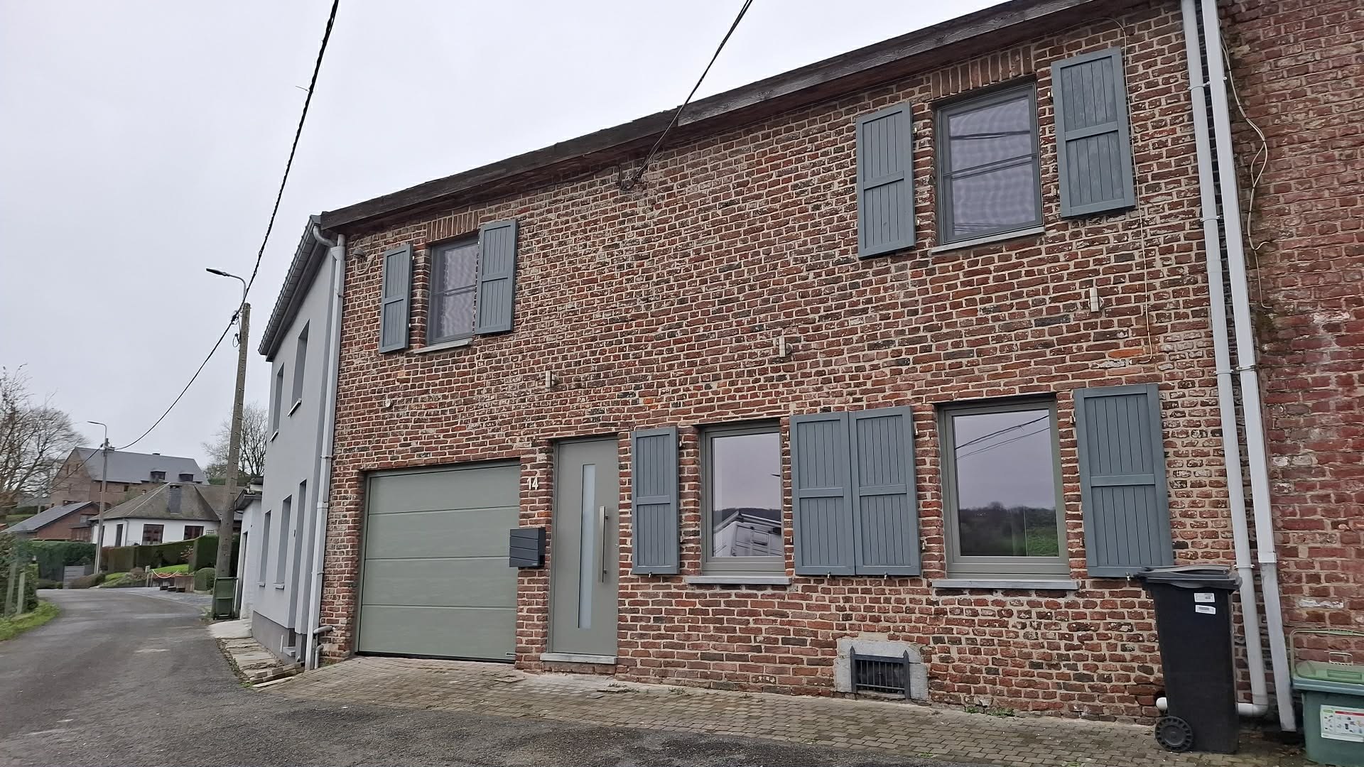 Maison de rue en brique avec châssis et volets gris anthracite