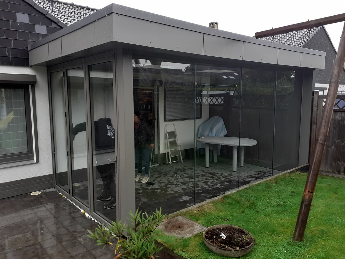 Pergola fermée par des parois vitrées coulissantes sur une pelouse