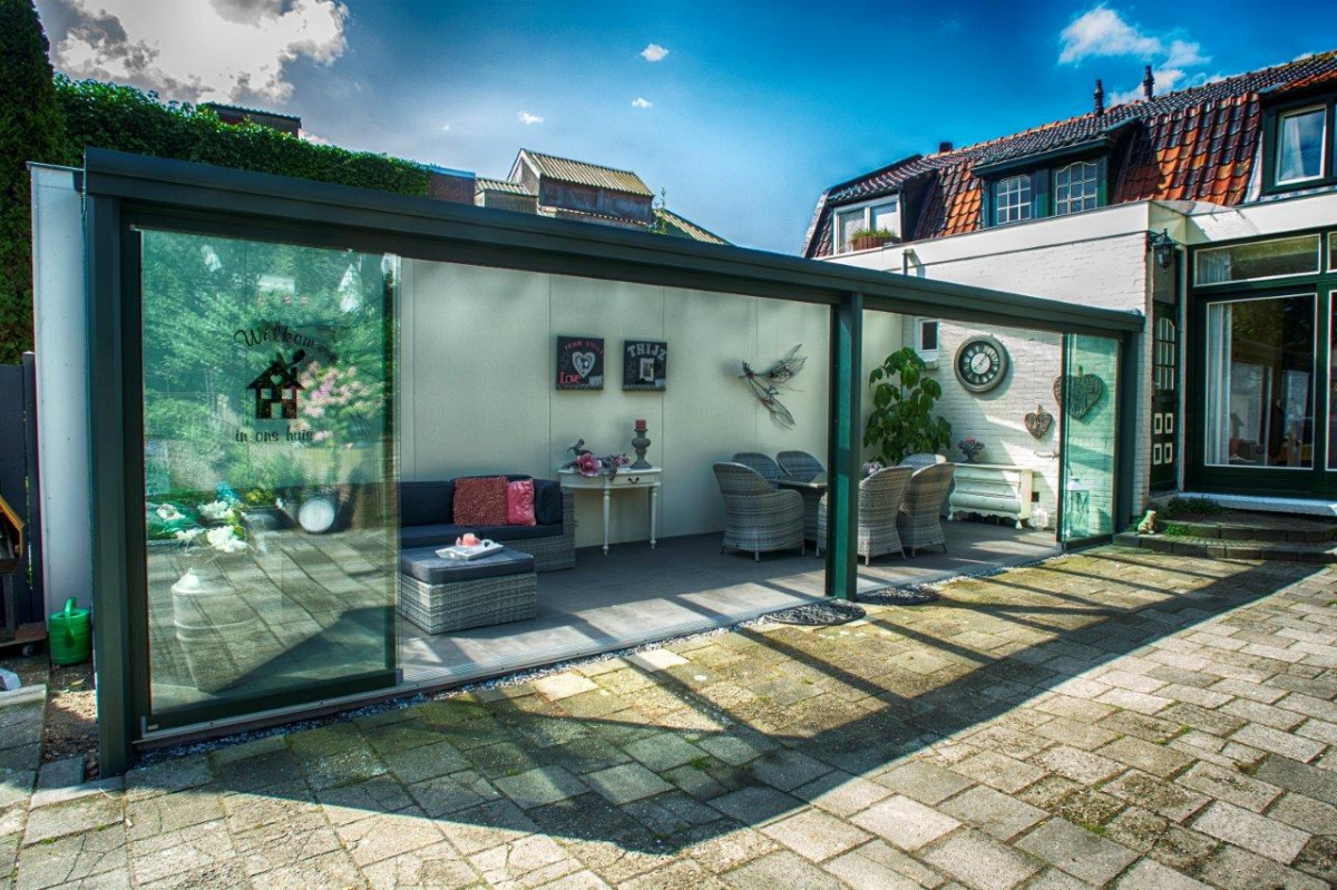 Pergola vitrée avec parois coulissantes sur terrasse pavée