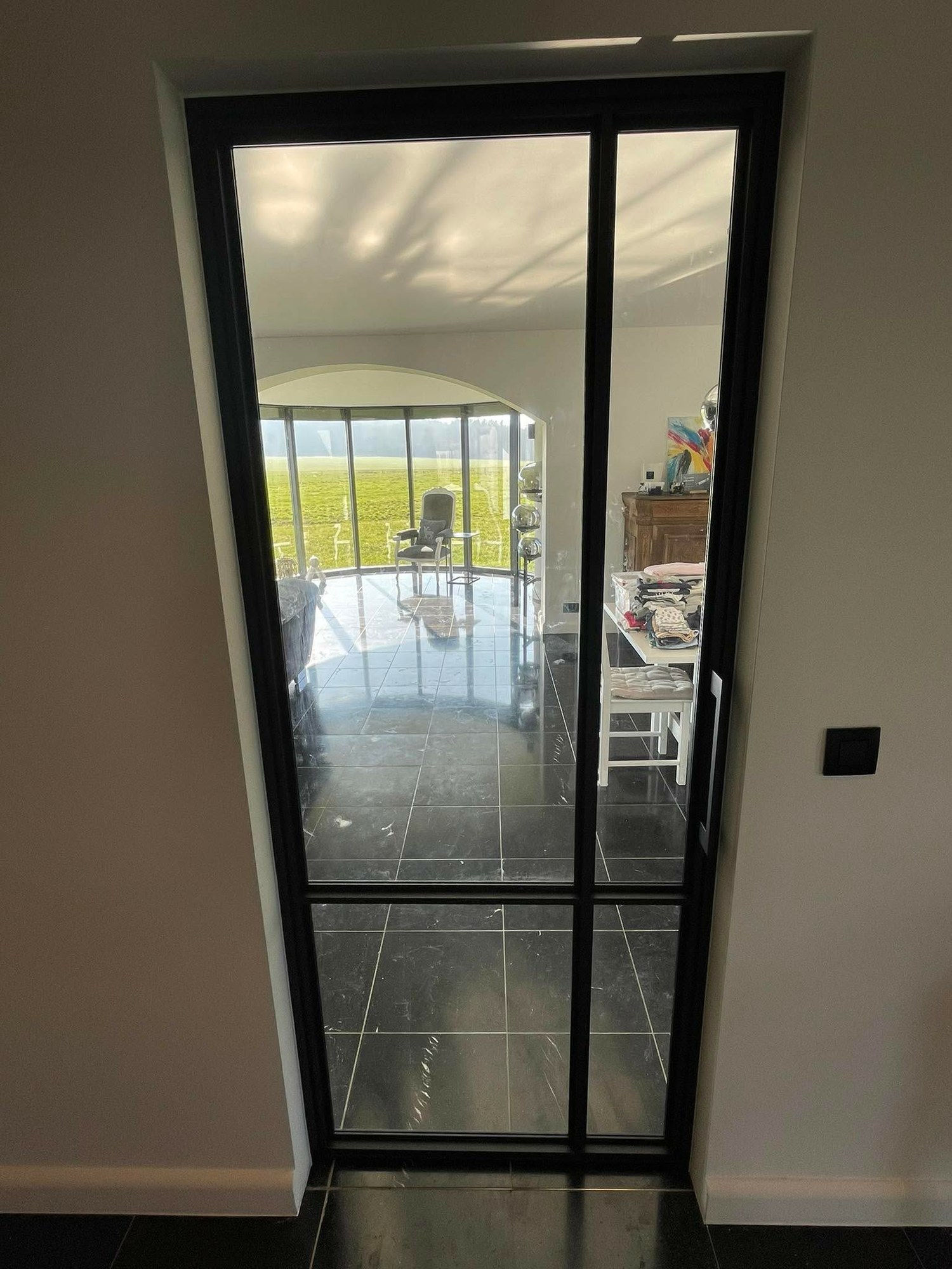 Porte intérieure en verre et aluminium noir ouvrant sur un séjour
