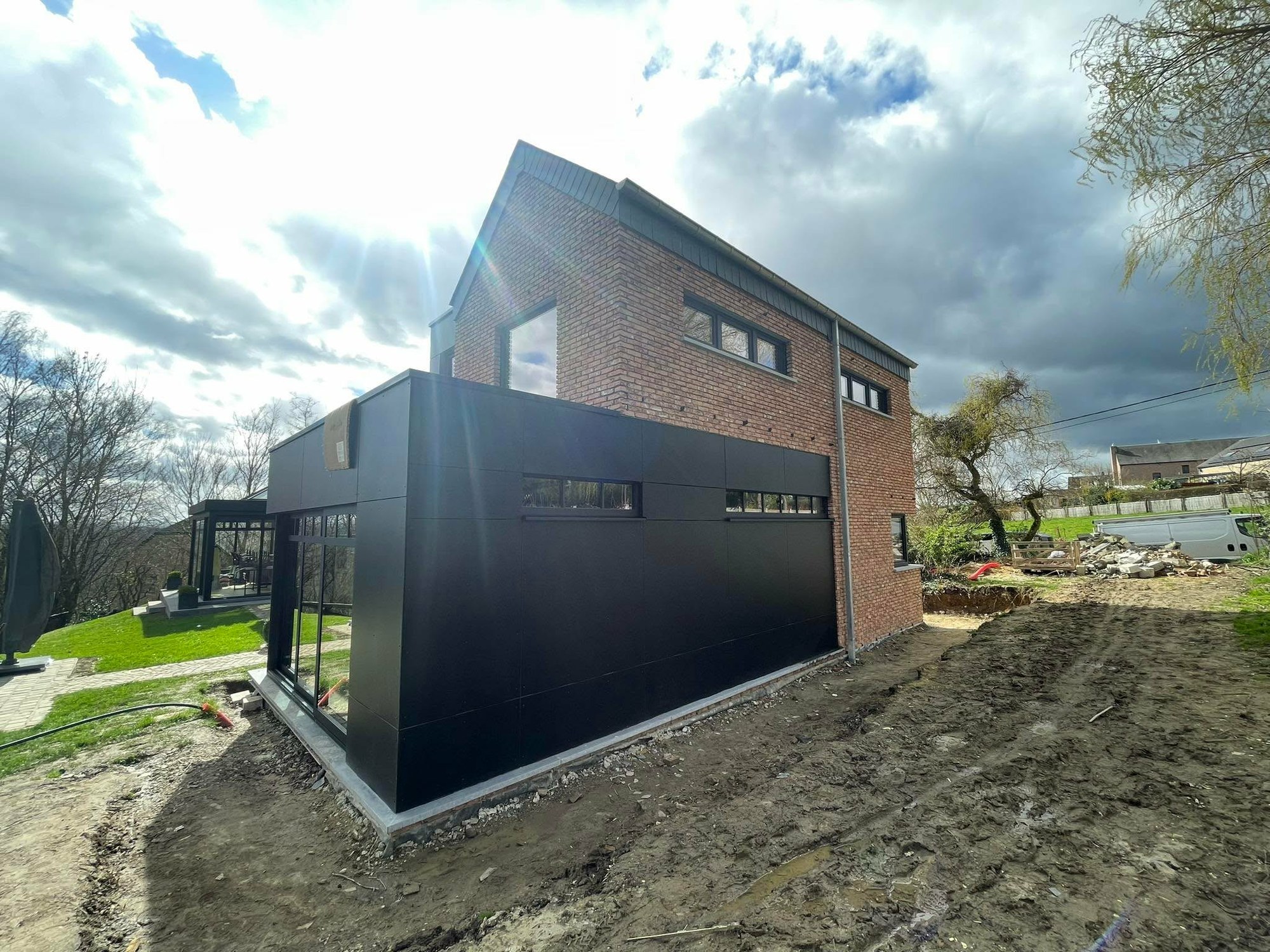 Extension noire vitrée accolée à une maison en brique