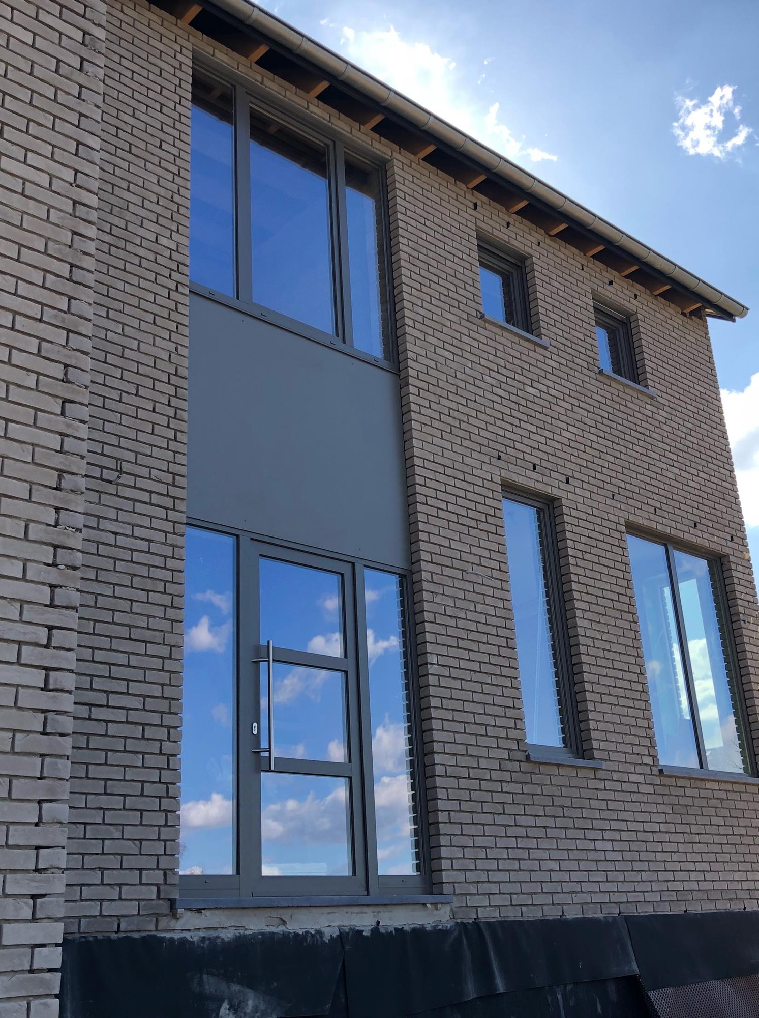 Façade contemporaine en brique claire avec grands vitrages fixes