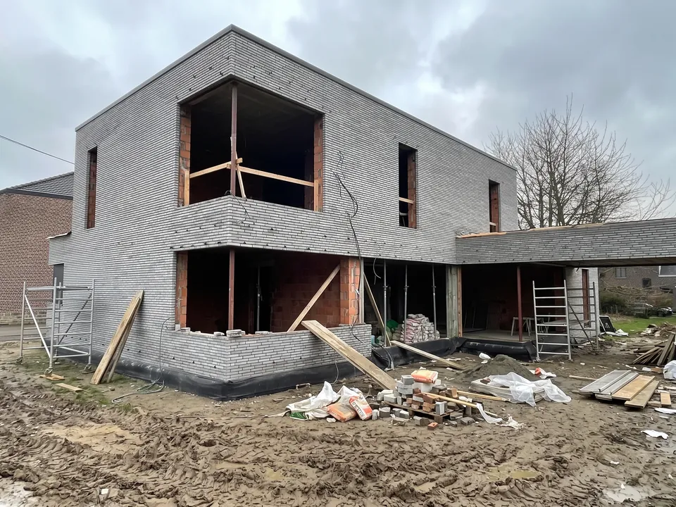 Avant travaux — Maison contemporaine en brique claire avec de grandes baies vitrées aluminium noir et une pelouse neuve